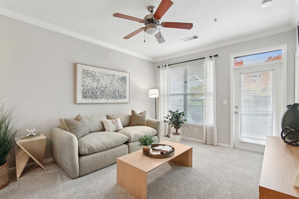 A living room with a grey couch, a coffee table, and a ceiling fan.