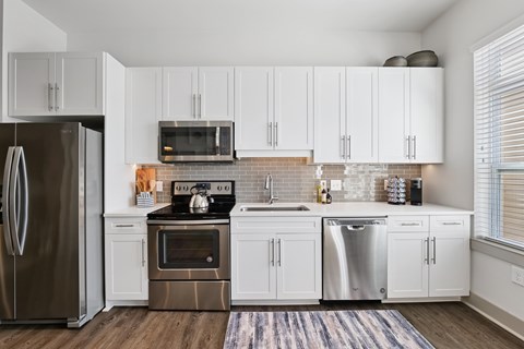 A modern kitchen with white cabinets and stainless steel appliances.