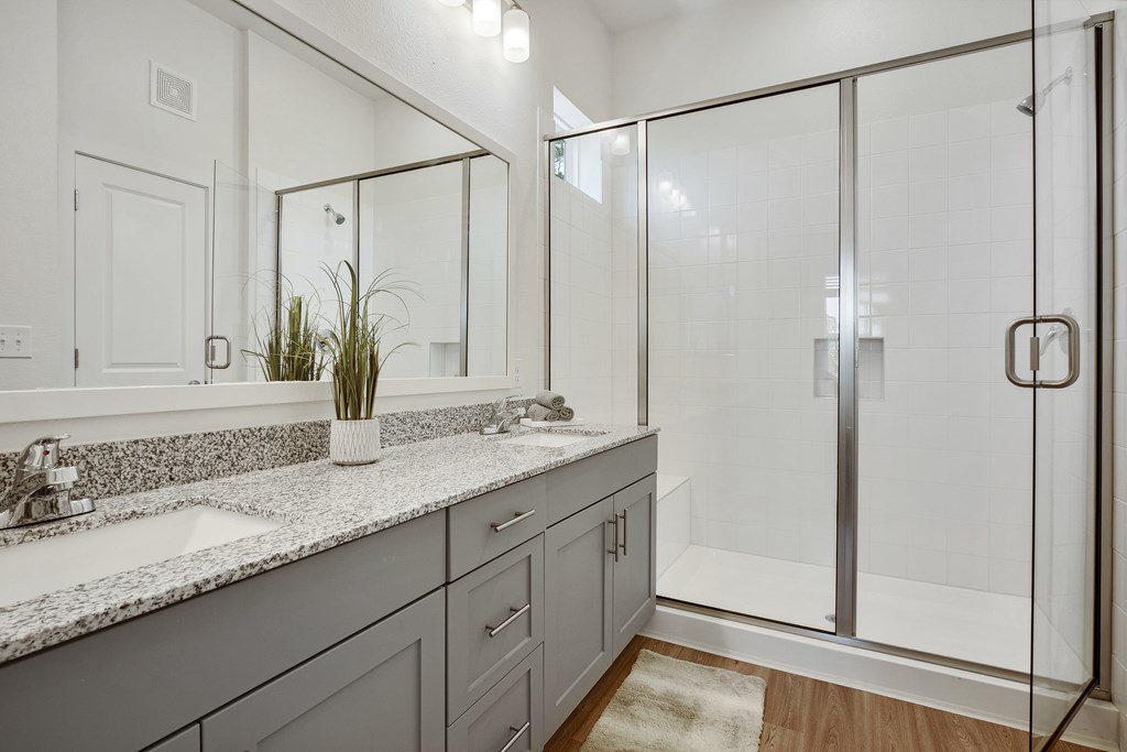 a bathroom with two sinks and a shower with a glass door