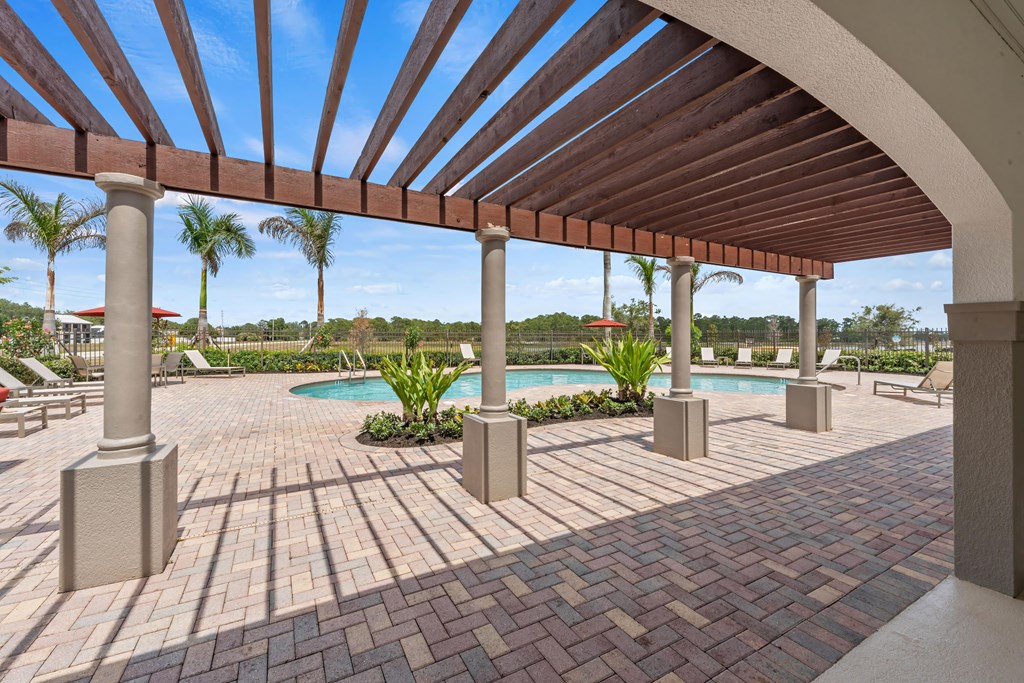 a covered patio with a pool and palm trees