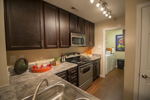 A kitchen with brown cabinets and a granite counter top.