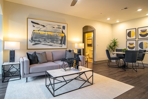 A living room with a grey couch, a coffee table, and a painting on the wall.