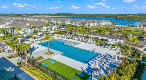 A large swimming pool surrounded by lounge chairs and umbrellas is the focal point of a resort-like setting.