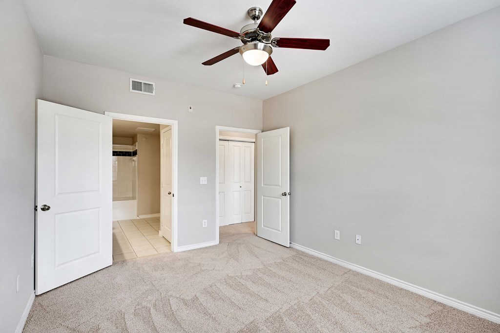 an empty living room with a ceiling fan and a door to a closet