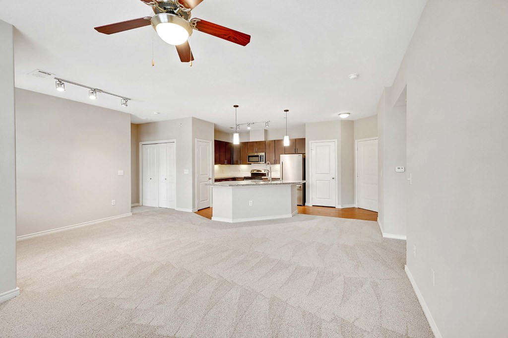 an empty living room and kitchen with a ceiling fan