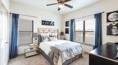 A bedroom with a bed, nightstand, and a ceiling fan.