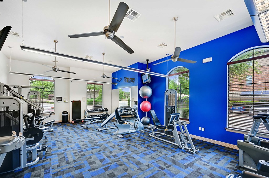 a gym with a blue wall and a ceiling fan
