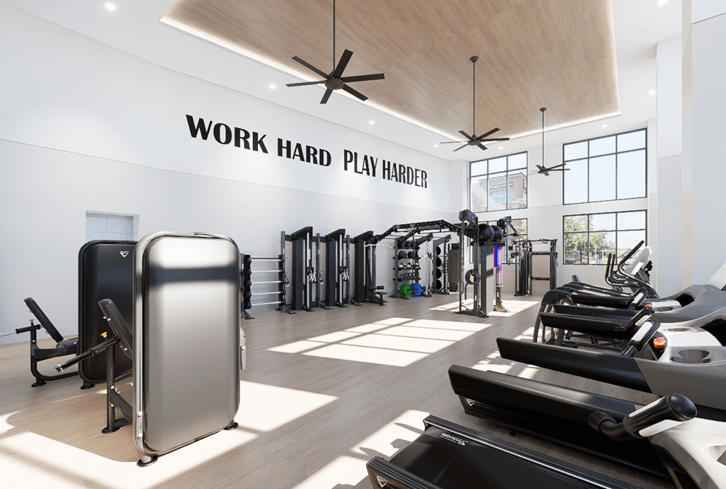 A gym with a variety of equipment and a sign that says "Work Hard Play Harder".