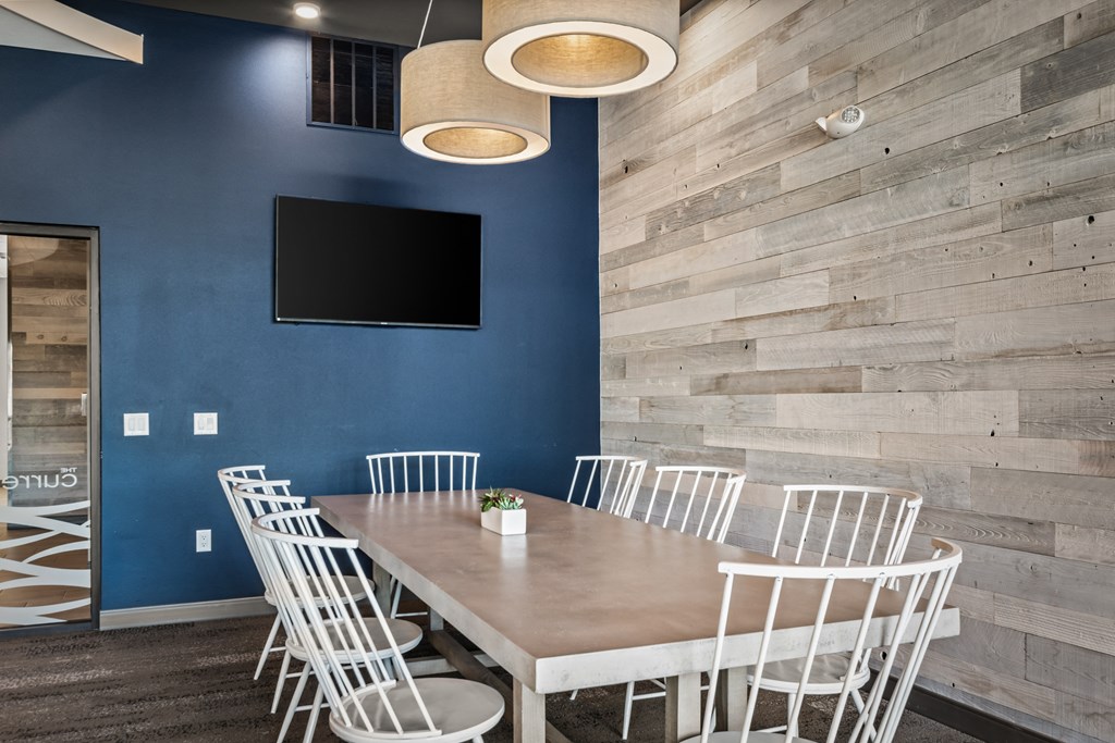 a dining room with a table and chairs and a tv on the wall