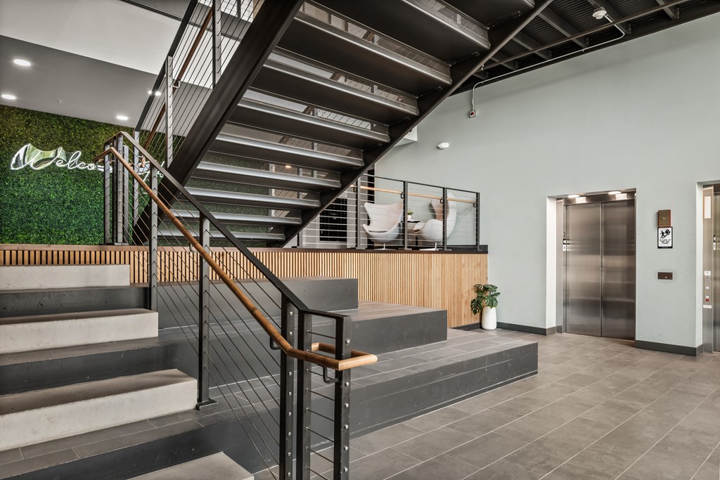 the lobby of a building with a staircase and a green wall