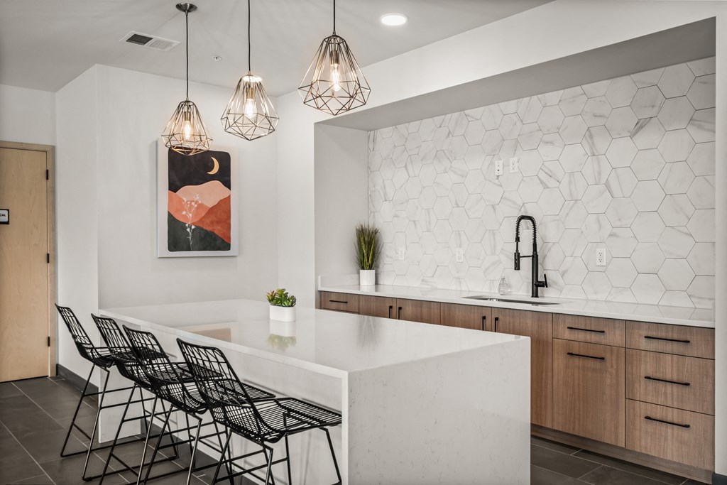 a kitchen with a white counter top and black chairs