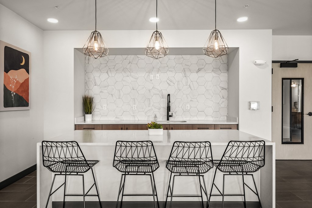 a kitchen with four bar stools in front of a white counter and a wall