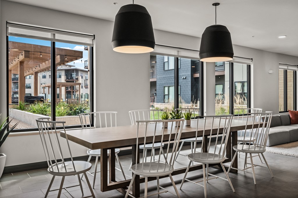 a dining room with a wooden table and chairs and large windows