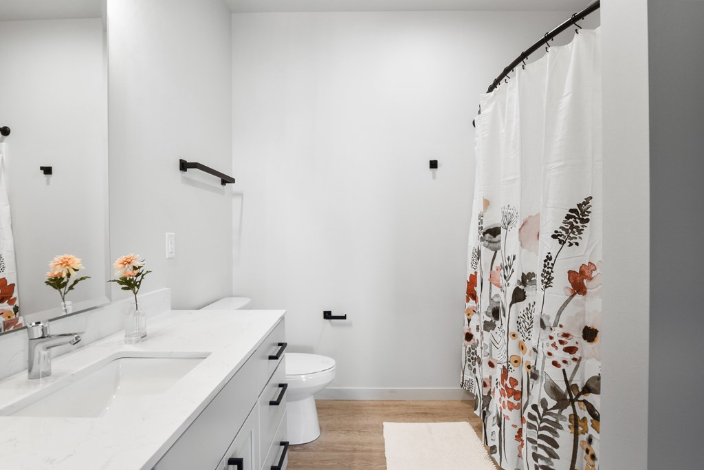 A white bathroom with a floral shower curtain.