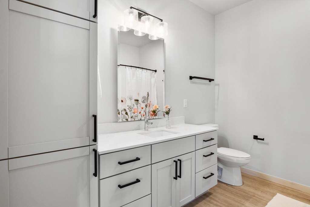A white bathroom with a toilet, sink, and mirror.