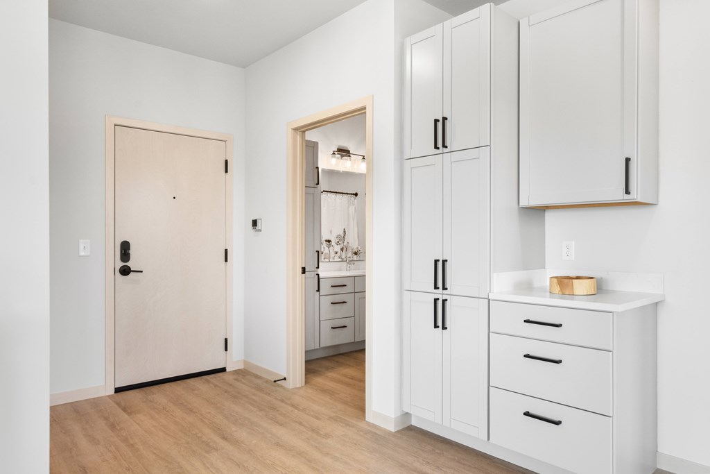 A kitchen with white cabinets and a wooden floor.