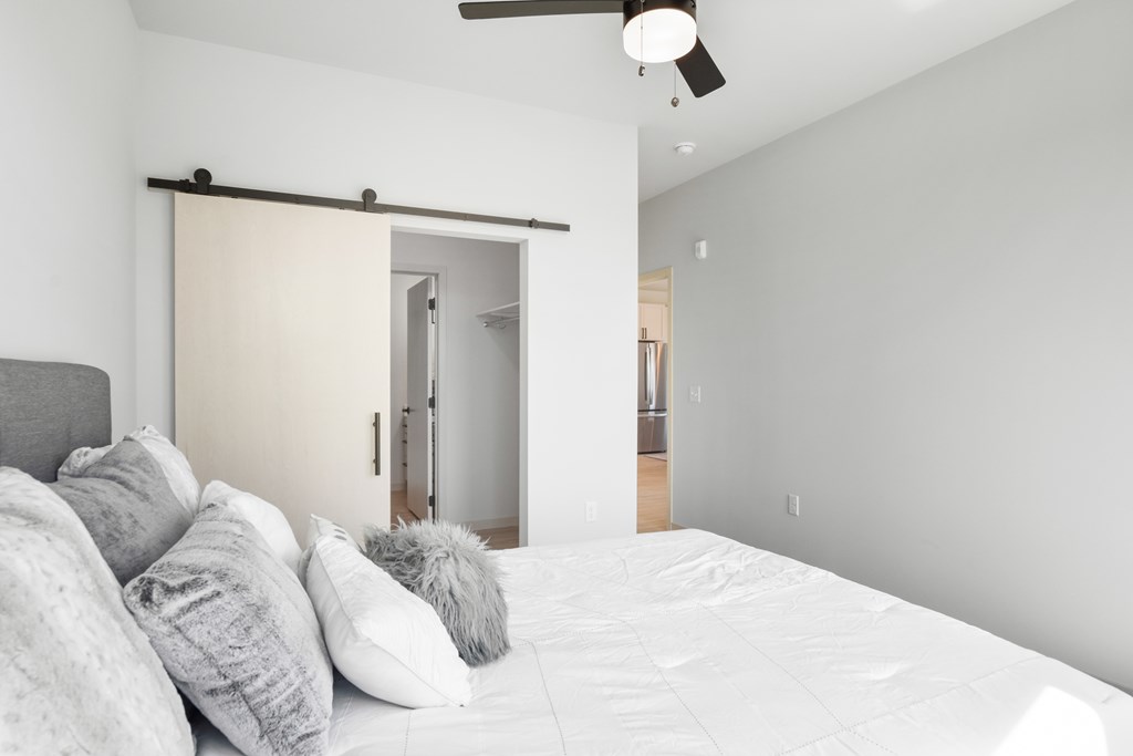 A bedroom with a bed, pillows, and a sliding door.