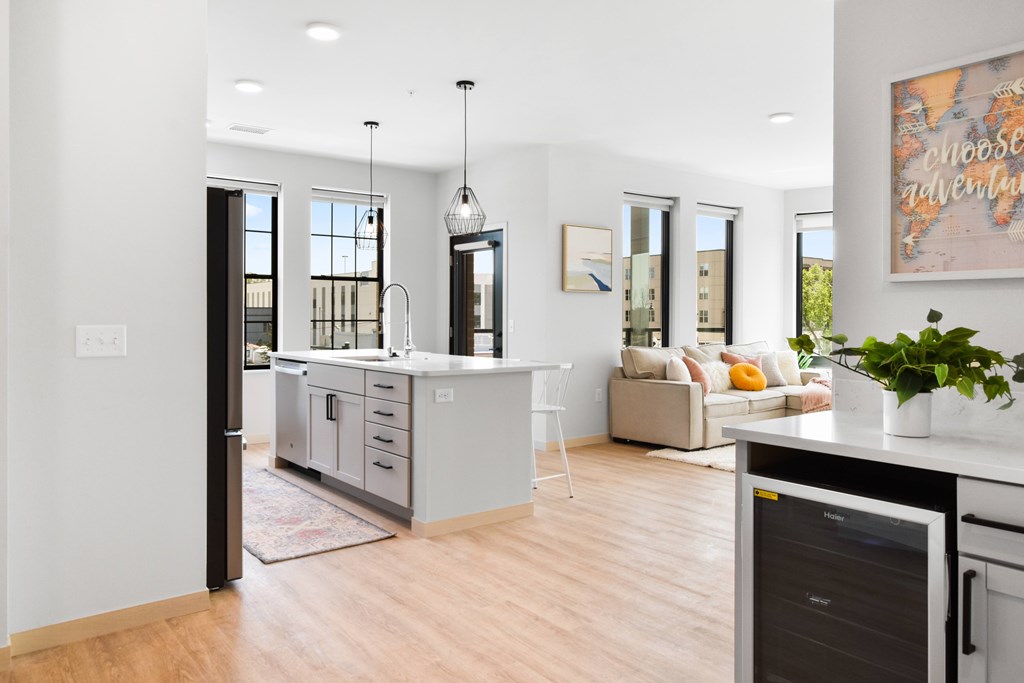 A modern kitchen with a large island and a dining area in the background.