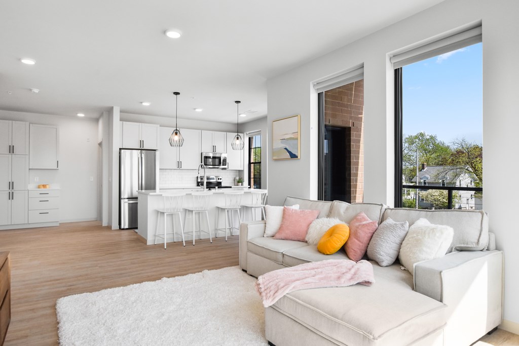 A modern living room with a kitchen in the background.