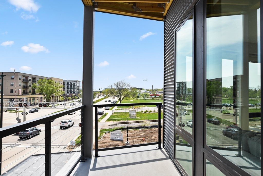 A view from a balcony looking out at a street with cars and buildings.