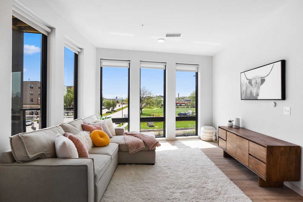 A living room with a grey couch and a painting of a cow on the wall.