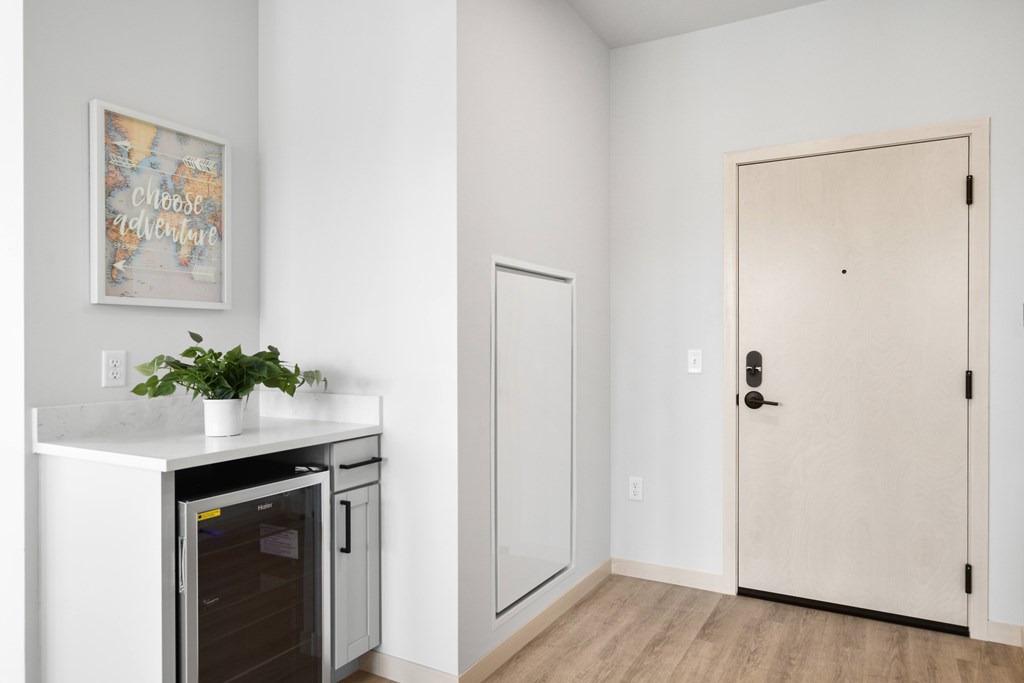 A kitchen with a fridge, a plant, and a picture on the wall.