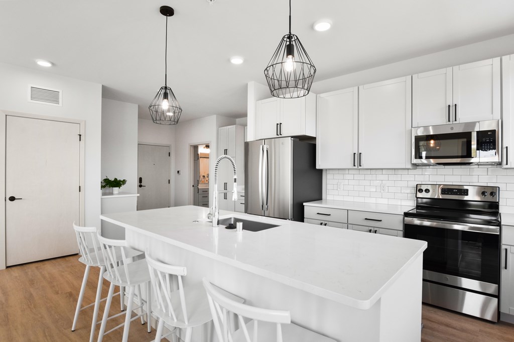 A modern kitchen with white cabinets and a white island.