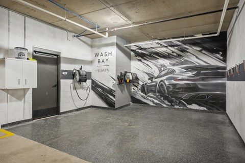A car wash bay with a large mural of a car on the wall.