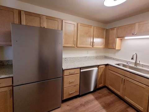 A kitchen with a stainless steel refrigerator and wooden cabinets.