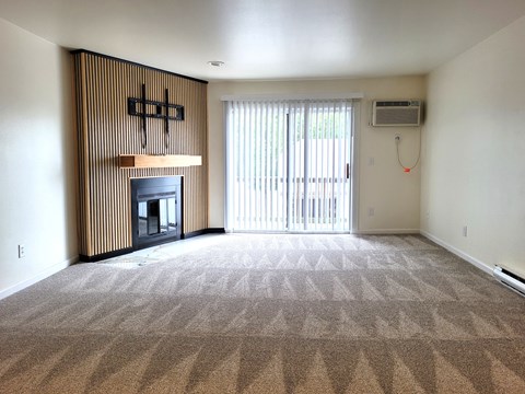 A living room with a fireplace and carpeted floor.