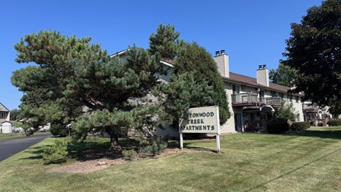 A sign in front of a building that says "Atwoodwood Apartments".