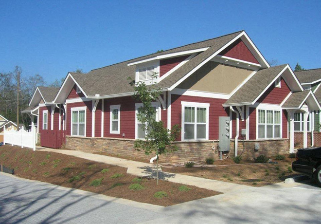 A red house with a white trim and a brown roof.