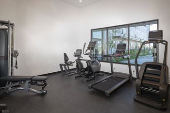 a gym with various cardio equipment on the floor and a window at The Landing at 1001 NP, Fargo, ND 58102