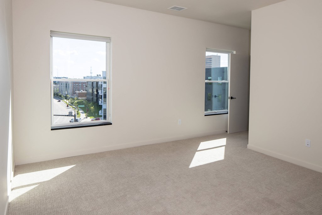 an empty living room with two windows and a city view at Riverhouse Apartments, Fargo, ND