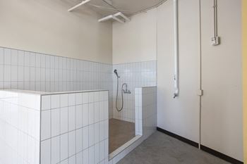a bathroom with white tiled walls and a shower in it at Riverhouse Apartments, Fargo, ND 58102