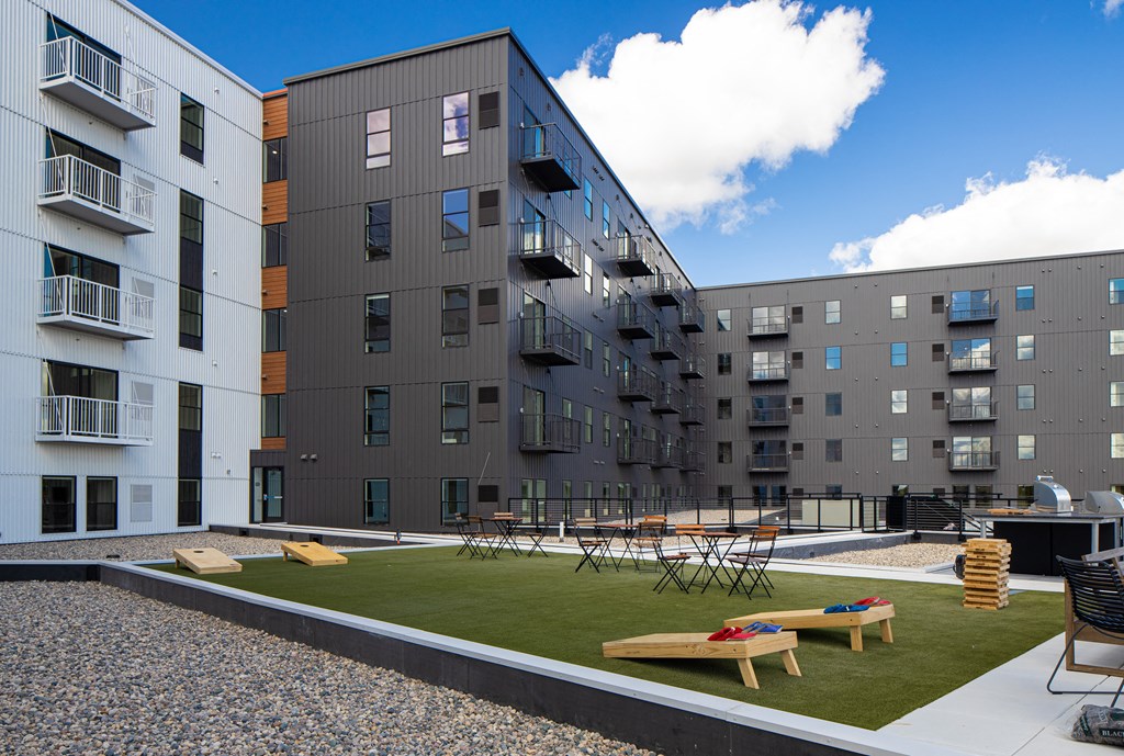 an exterior view of an apartment complex with tables and grass at Riverhouse Apartments, Fargo, ND