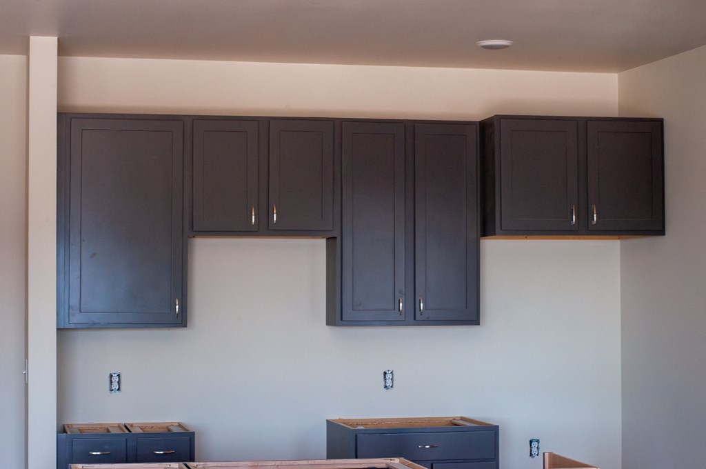 a kitchen with blue cabinets and white walls and dark blue cabinets on top of it