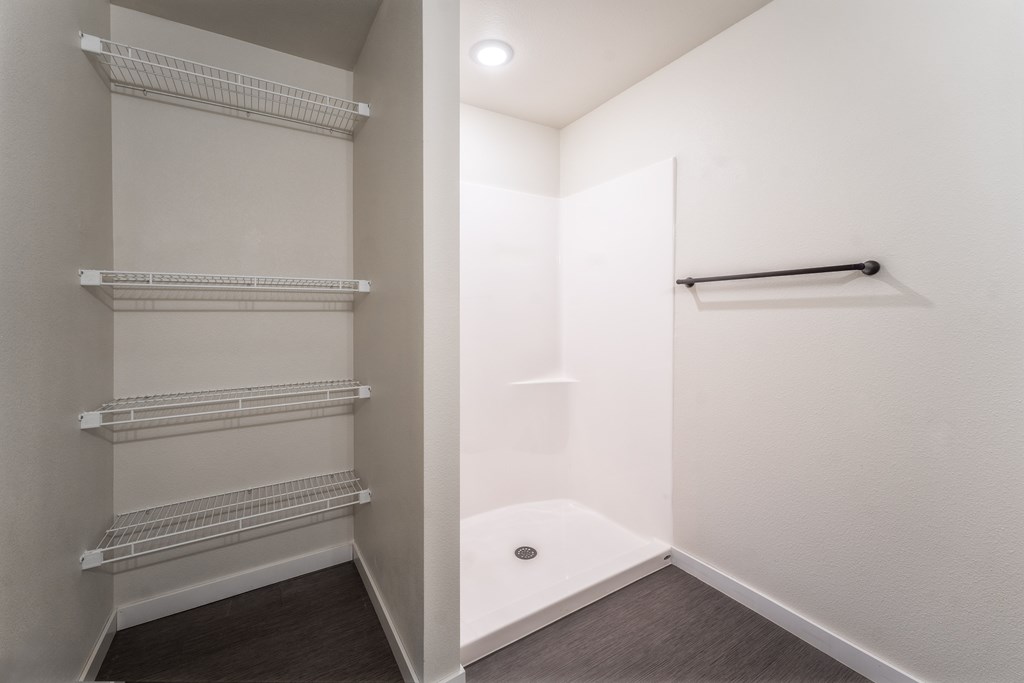 A white closet with shelves and a towel bar. at Unite Apartments, North Dakota