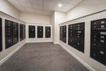 A row of black mailboxes are lined up on a wall.