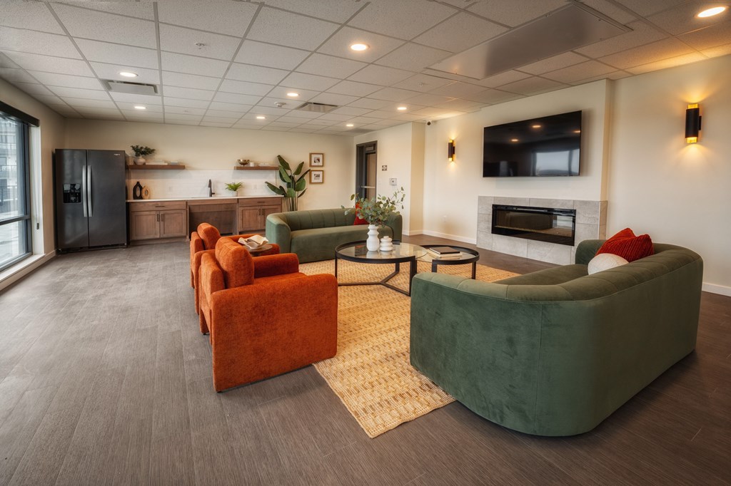 A living room with a grey floor and a green couch. at Unite Apartments, Fargo, ND