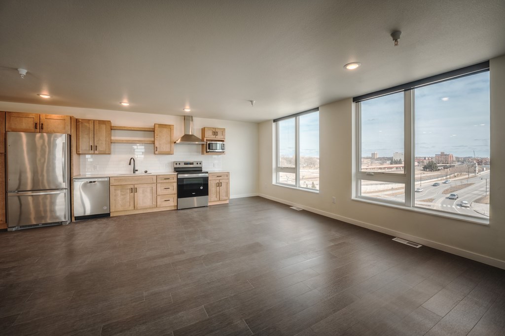 A kitchen with wooden floors and a large window overlooking a city street. at Unite Apartments, North Dakota