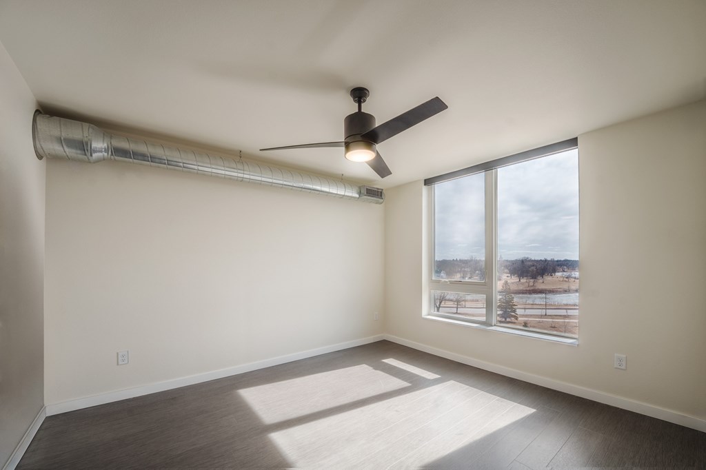 A room with a ceiling fan and a window overlooking a snowy landscape. at Unite Apartments, Fargo, ND