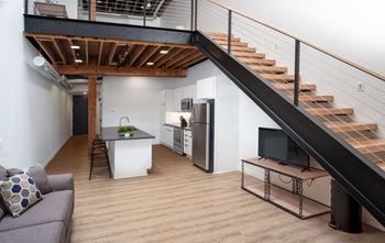 a living room with a staircase and a kitchen at Bostad Apartments, Fargo, ND 58102