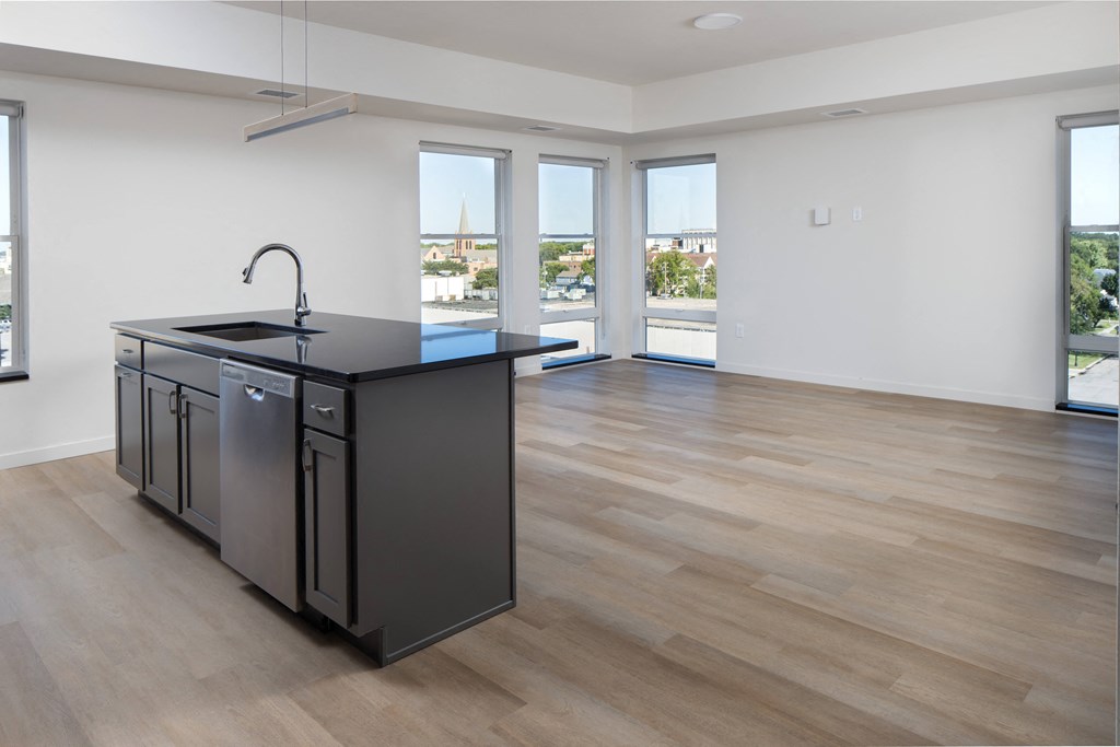 an open kitchen and living room with a large window and a black counter top at Riverhouse Apartments, Fargo, ND 58102