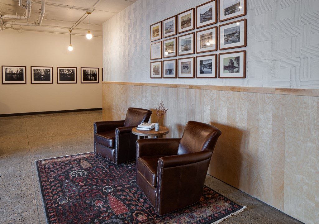 two leather chairs in a room with pictures on the wall at Riverhouse Apartments, Fargo, North Dakota
