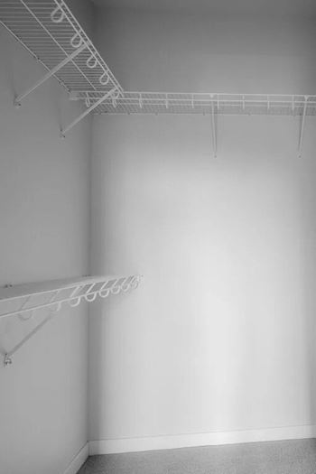 an empty room with a white wall and a wire rack on the ceiling