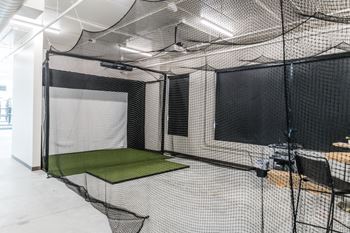 a batting cage in a room with nets and a table and chairs at Riverhouse Apartments, North Dakota