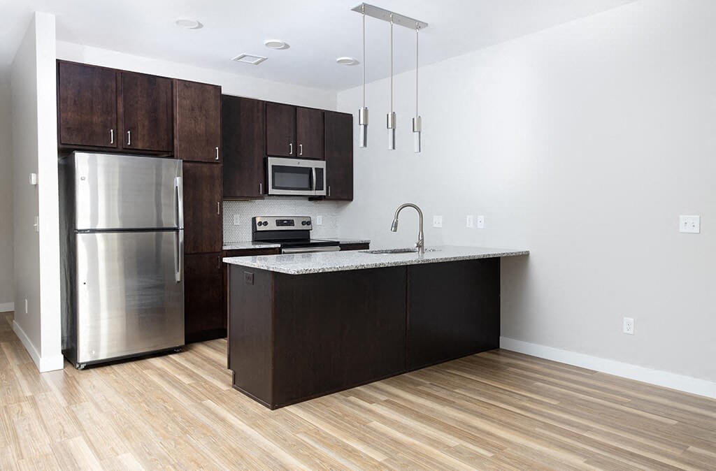 a kitchen with dark wood cabinets and stainless steel appliances  at RoCo Apartments, Fargo, ND, 58102