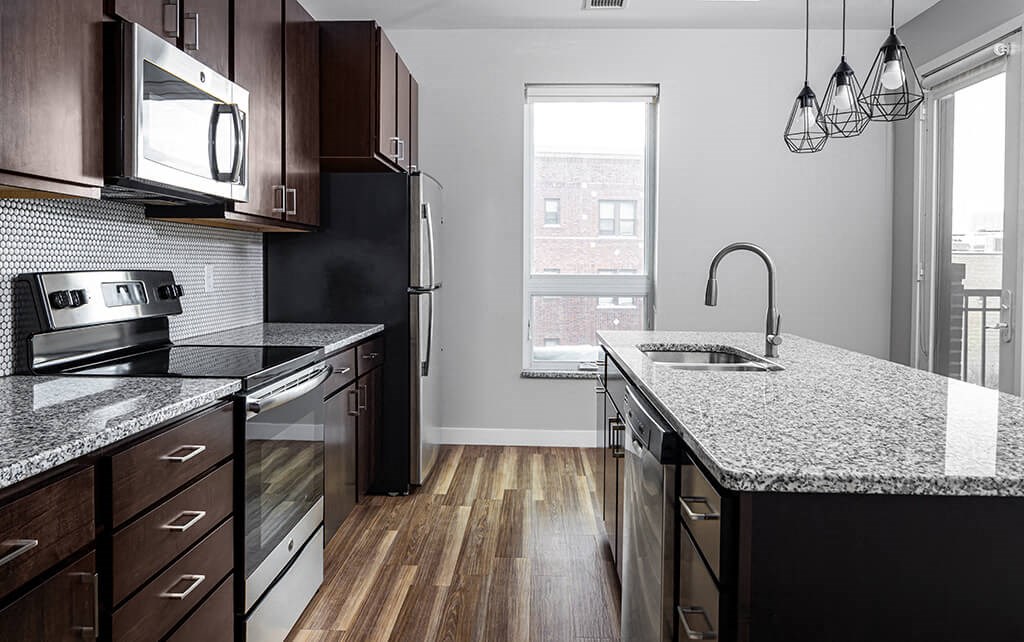 a kitchen with granite countertops and dark wood cabinets  at RoCo Apartments, Fargo, North Dakota, 58102