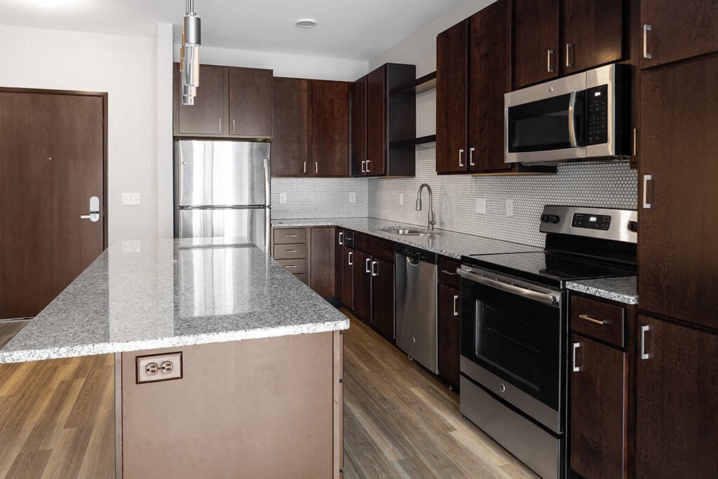 a kitchen with dark wood cabinets and stainless steel appliances  at RoCo Apartments, Fargo, North Dakota 58102